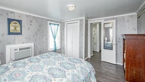 A bedroom with a bed, a wardrobe, a mirror, and a door leading to another room.