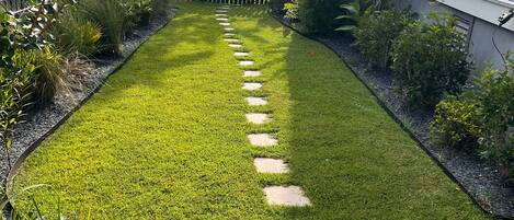 A well-maintained garden with a stone pathway leading to a wooden fence.