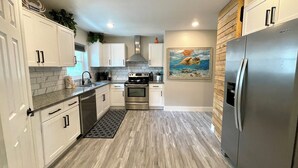 Une cuisine moderne avec des armoires blanches, des appareils en acier inoxydable et un plancher en bois.