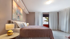 A hotel room with a bed, a round table with a lamp, a painting on the wall, and a view of the beach through the window. - Casa do Mar praia de Cotovelo Carpediem (Parnamirim)