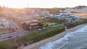 An aerial view of a coastal hotel with multiple buildings, a beach, and a road with vehicles and pedestrians. - Casa do Mar praia de Cotovelo Carpediem (Parnamirim)