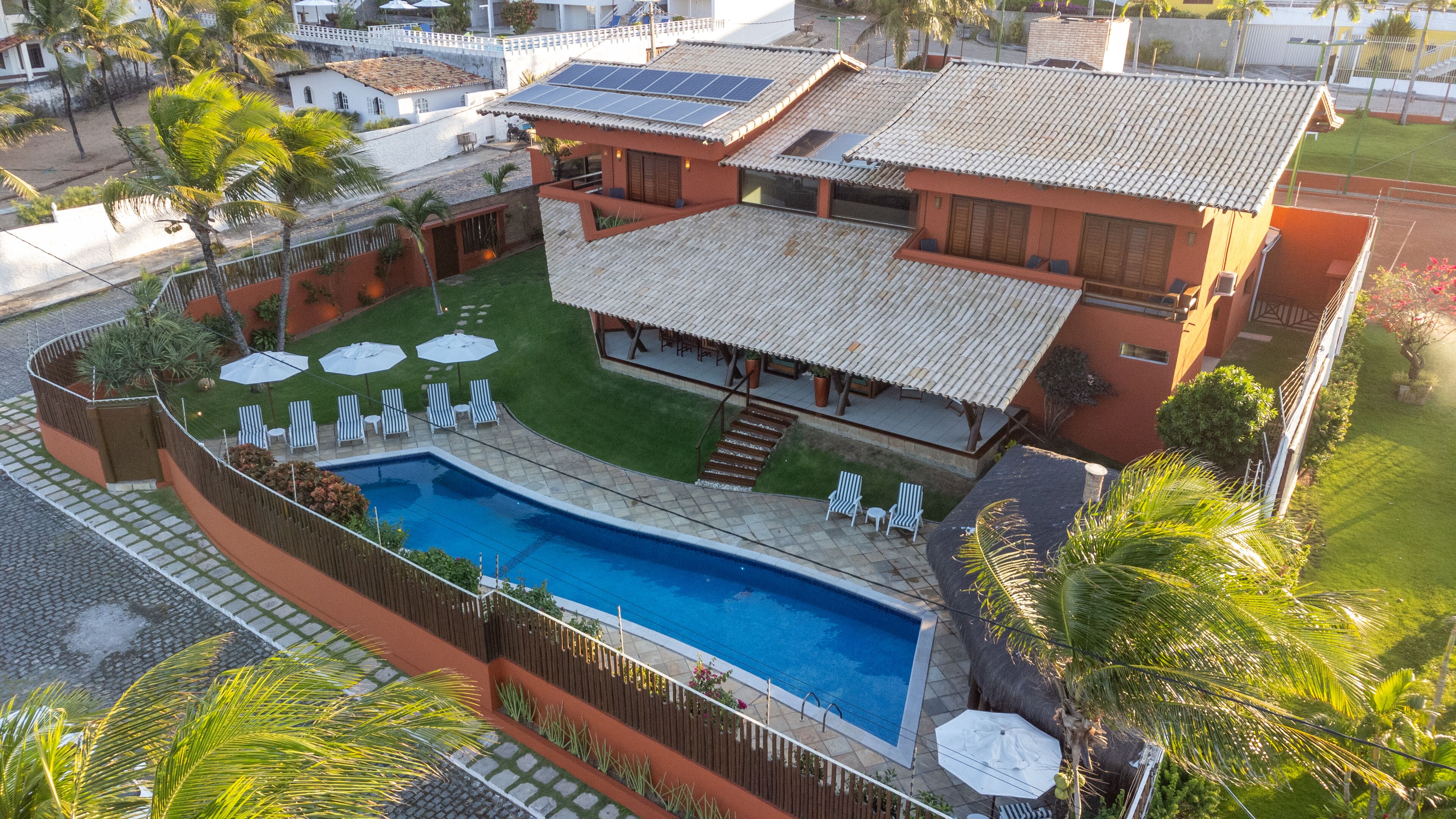 Una proprietà residenziale con piscina, patio coperto e giardino recintato.