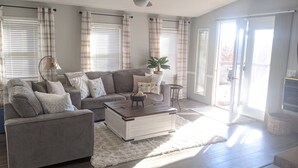 A living room with a gray sofa, a coffee table, and a plant. - Lake view retreat steps to Badin Lake! Pool, Beach, Restaurant/Bar & Boat Launch (New London)