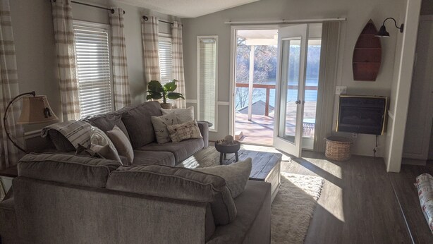 A living room with a grey sectional sofa, a ceiling fan, a potted plant, and a view of a deck and outdoor area. - Lake view retreat steps to Badin Lake! Pool, Beach, Restaurant/Bar & Boat Launch (New London)