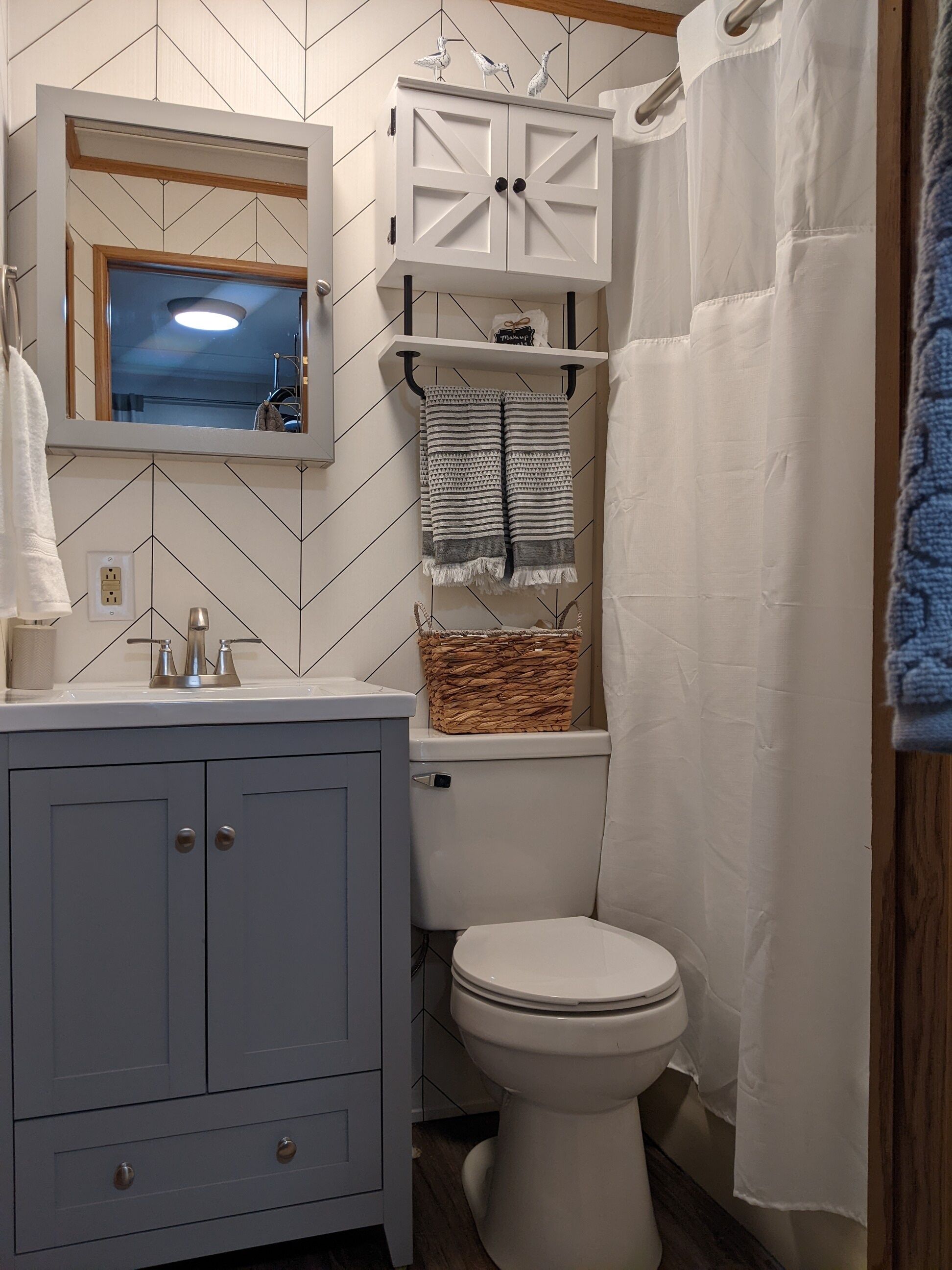 A bathroom with a white vanity, a mirror, a white toilet, and a shower curtain.