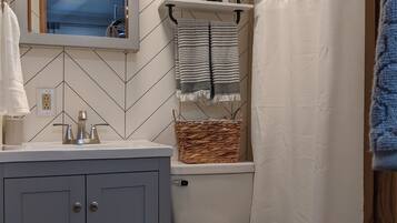 A bathroom with a white vanity, a mirror, a white toilet, and a shower curtain.
