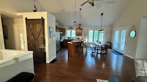 A spacious kitchen with a large island, wooden flooring, and a farmhouse-style door. - Former Lottery Home Near Private Beach & River (Grand Bend)