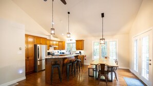 A spacious kitchen with wooden cabinets, a stainless steel refrigerator, and a central island with bar stools. - Former Lottery Home Near Private Beach & River (Grand Bend)