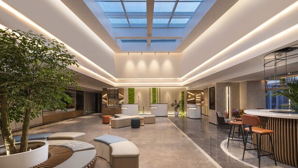 Eine großzügige Lobby mit Oberlicht, Sitzbereichen und einer Rezeption.