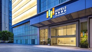 Ein modernes Hotelgebäude mit einem gut sichtbaren 'EVEN HOTELS'-Schild, großen Glasfenstern und einer gut beleuchteten Fassade.