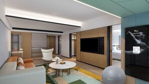 A modern hotel room with a sofa, a round coffee table, a TV, and a fitness ball. - EVEN Chengdu Jinniu by IHG (Chengdu)