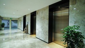 Eine moderne Lobby mit Marmorböden, Aufzügen und Zimmerpflanzen.