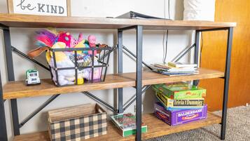 A wooden shelf unit with a 'be KIND' sign, holding various board games and a toy car.