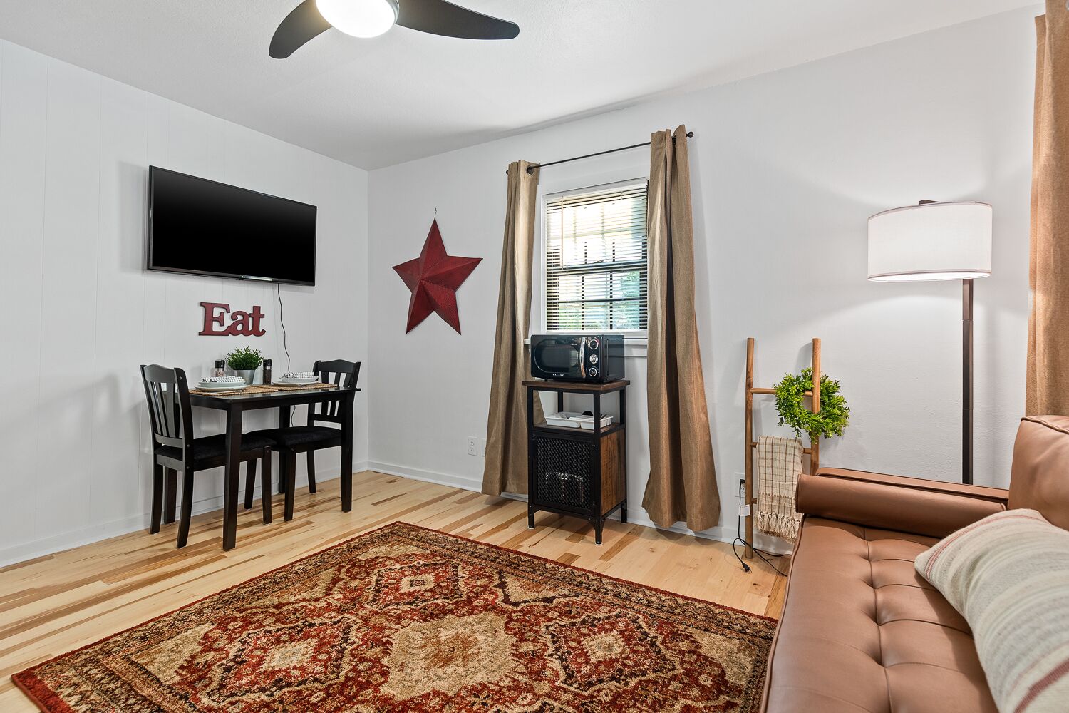 A living room with a TV, a star decoration, a dining area with a table and chairs, a sofa, and a rug.