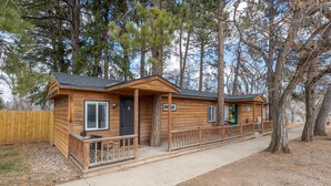A two-story log cabin with a front porch and a covered walkway connecting the two units. - Spearfish Cottages (Spearfish)