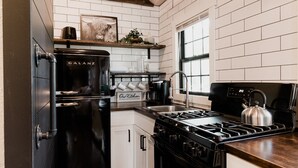A modern kitchen with white subway tiles, a black Galanz refrigerator, a stainless steel stove, and a wooden ceiling. - Spearfish Cottages (Spearfish)