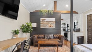 A modern living room with a brown leather sofa, wooden coffee table, and a large TV mounted on the wall. - Spearfish Cottages (Spearfish)