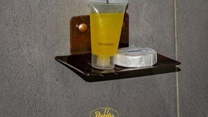 Estante de baño con una botella de champú, una pastilla de jabón y un cepillo de dientes.