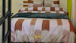 Una cama con una colcha a rayas, cabecera de madera y cortina verde.