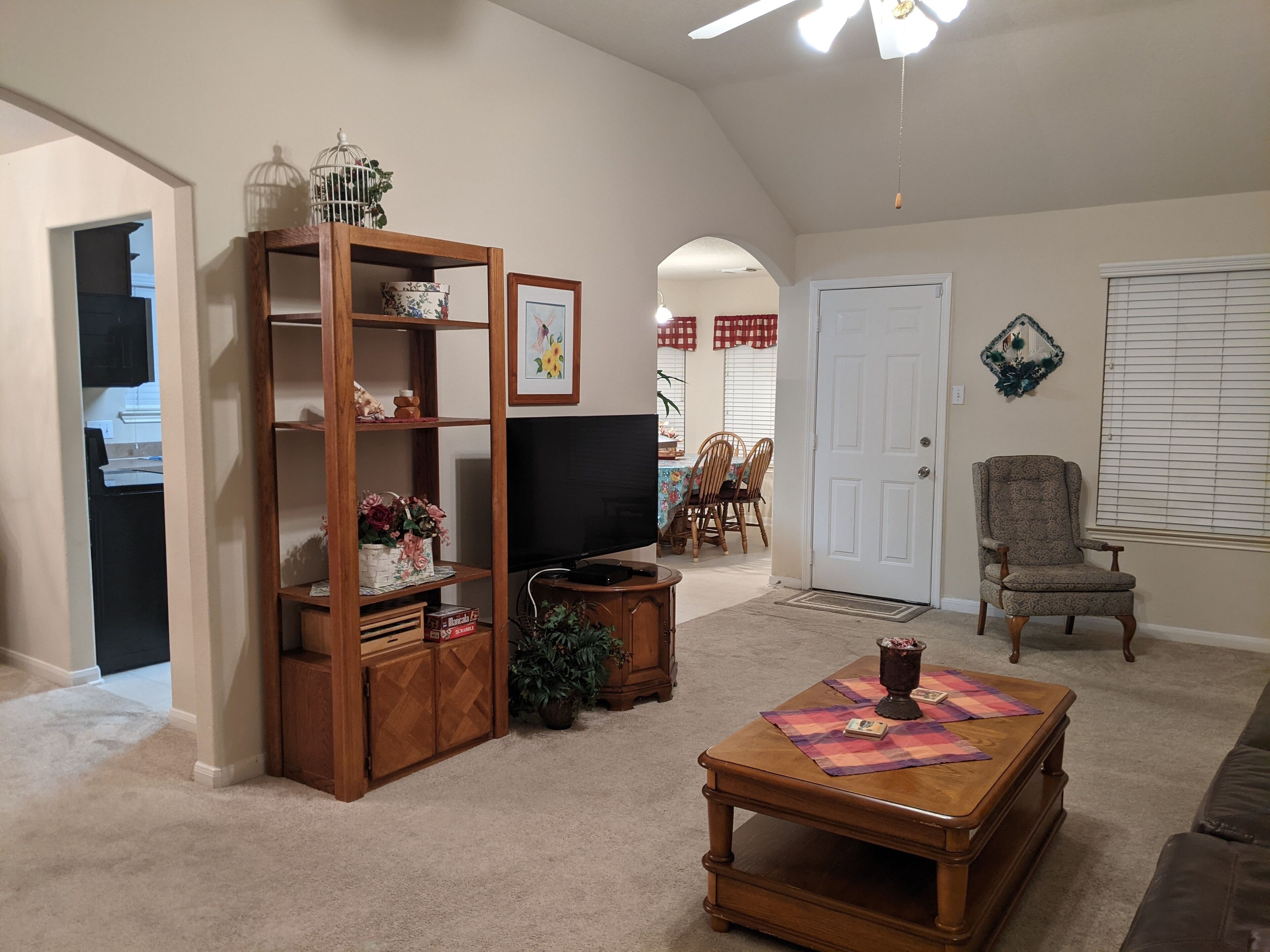A living room with a wooden entertainment center, a television, a coffee table, and a chair.