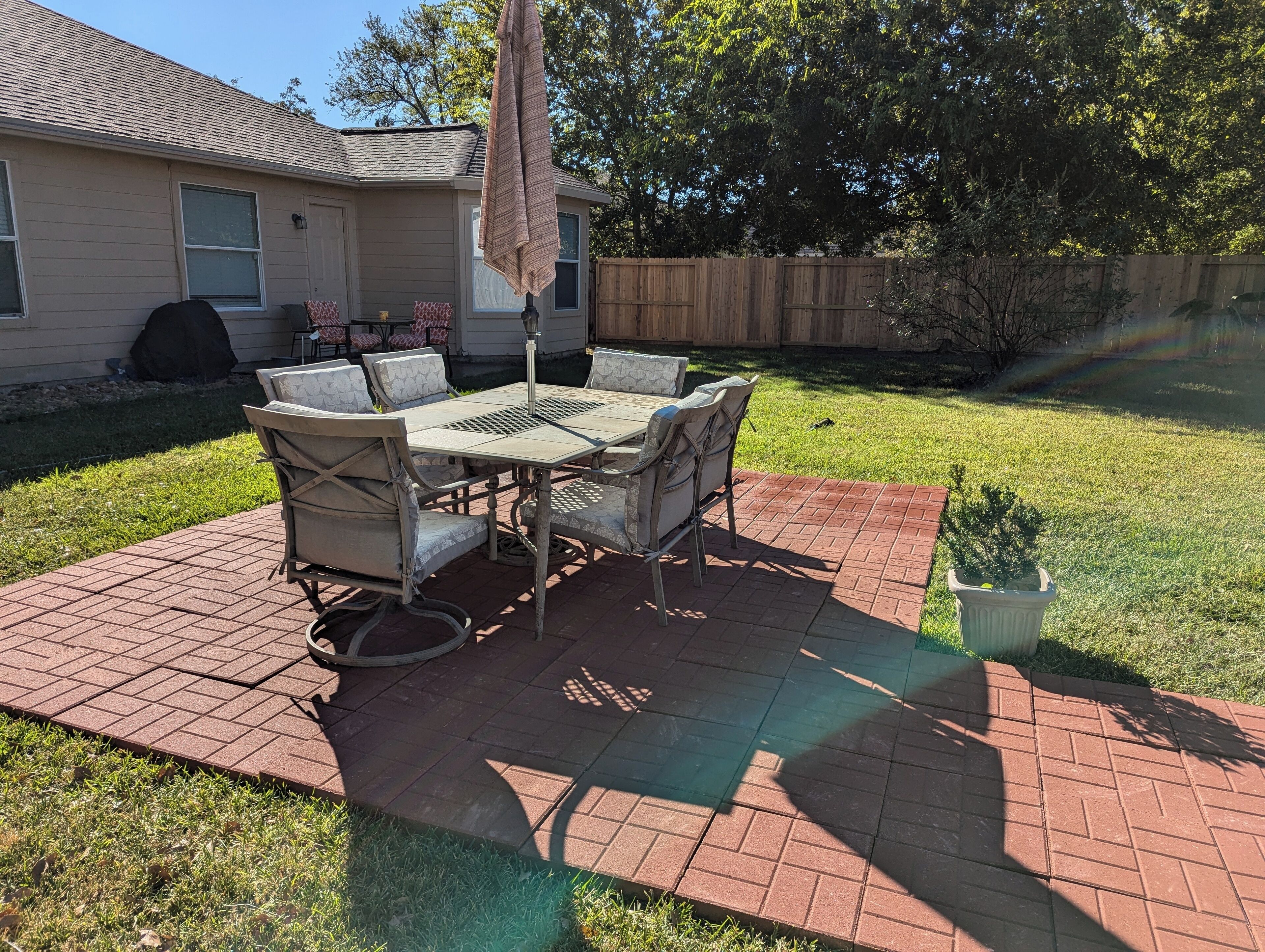 Une terrasse avec une table et des chaises, une serviette suspendue et une petite plante en pot.