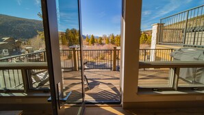 Un balcon offrant une vue sur un paysage montagneux, un espace extérieur aménagé et abrité, et une entrée sécurisée par un portail.