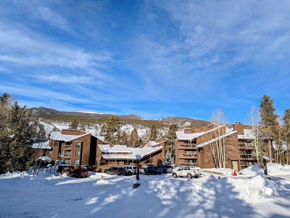 A snow-covered building complex with multiple floors and a ski slope in the background. - Wild Irishman 1032 (Keystone)