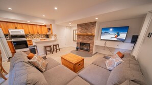 A modern living room with a fireplace, a television, and a kitchen area. - Wild Irishman 1032 (Keystone)