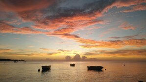 Une mer calme au coucher du soleil, avec des bateaux à l’ancre.