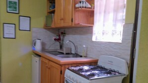 Une cuisine de taille réduite, dotée de meubles en bois, d’une cuisinière à gaz, d’un évier et d’un petit réfrigérateur.