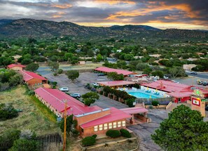 A hotel with multiple red-roofed buildings, a swimming pool, and a mountainous backdrop. - Pecos Trail Inn (Santa Fe)