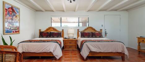 A bedroom with two beds, a window with blinds, a ceiling fan, and a poster on the wall.