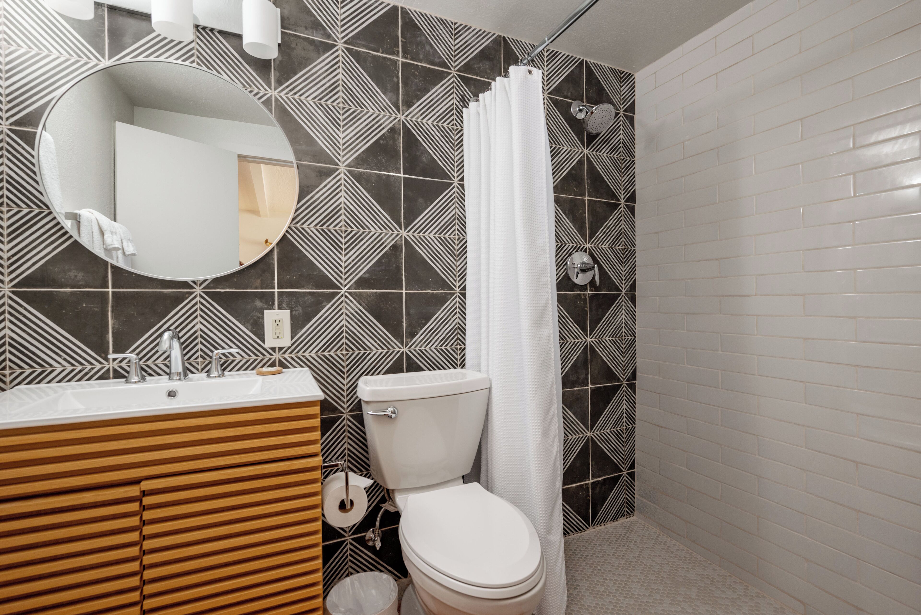 A bathroom with a modern design, featuring a sink, toilet, and shower area.