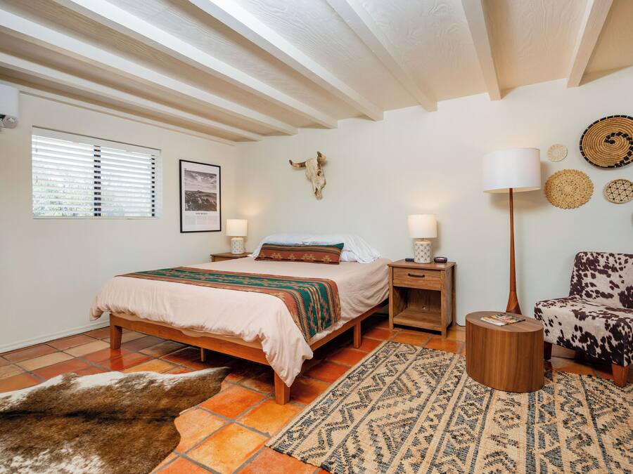 A bedroom with a bed, bedside tables, a lamp, a chair, and wall decorations.