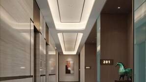 Un couloir d’hôtel moderne au design épuré, avec un plafond encastré et un panneau indiquant le numéro de la chambre 201.
