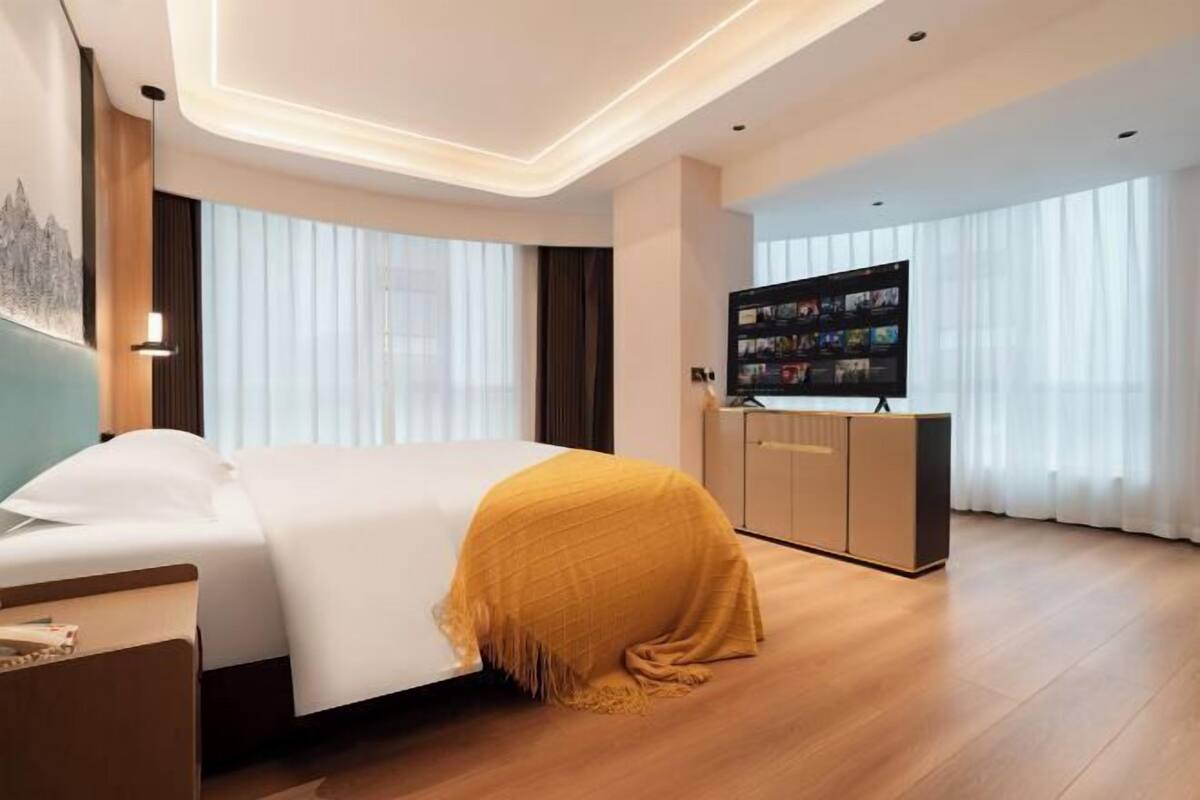 A hotel room with a bed, a TV, and a desk.