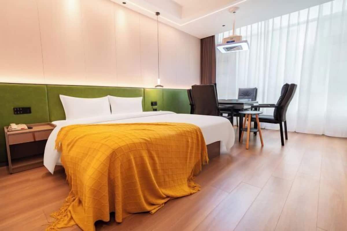 A hotel room with a bed, a desk, and a chair.