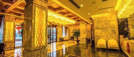 Un'ampia hall con pavimento in marmo lucido, una reception e un'area salotto con poltrone.