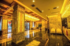 A spacious lobby with a polished marble floor, a reception desk, and a seating area with chairs. - Jiang Zhou Hotel (Hengyang)