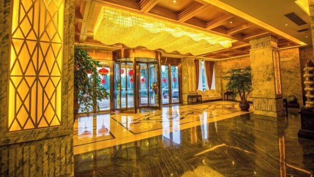 Un hall d’entrée doté d’un sol en marbre, d’un grand plafond décoratif et d’une porte d’entrée en verre.