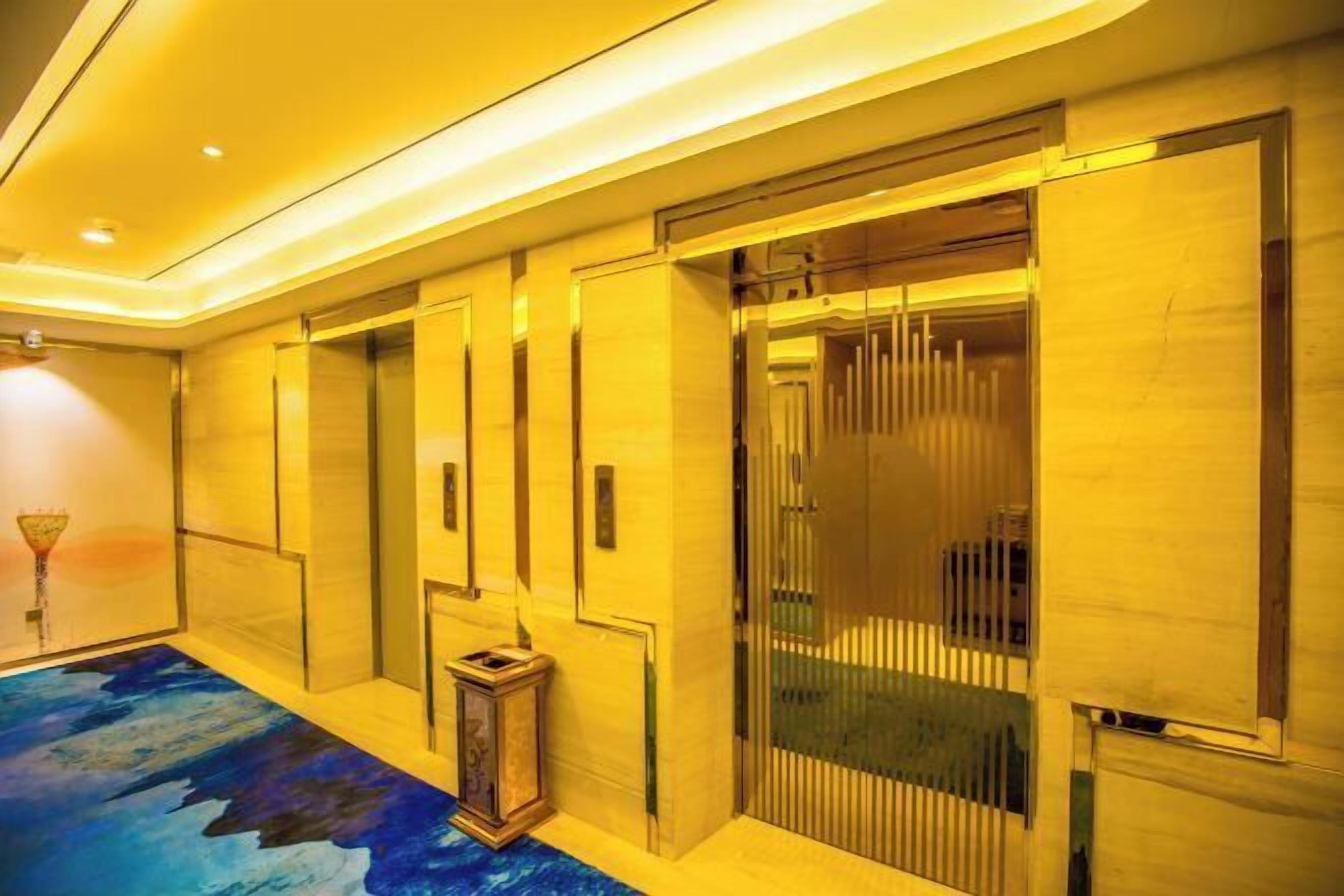 Un interior moderno con una paleta de colores azul y amarillo, que presenta un piso estampado, una pared de vidrio y un pilar de madera.