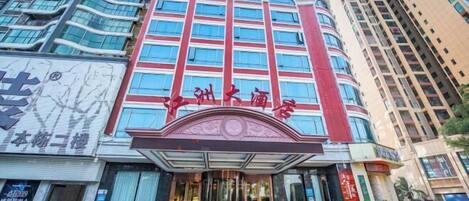 A hotel with a modern facade, featuring a prominent entrance with a curved overhang and large windows.