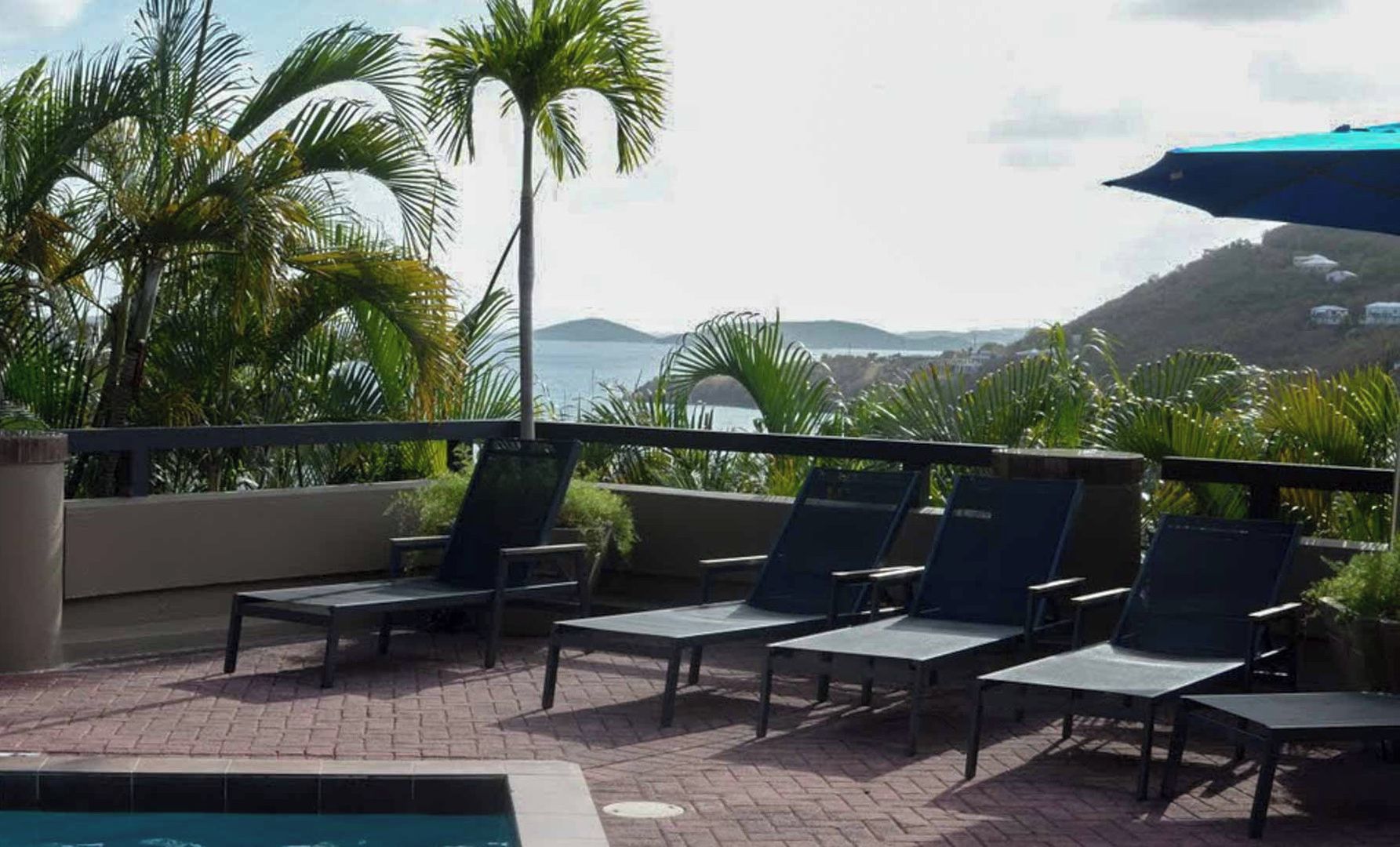 A rooftop pool area with lounge chairs and a view of the ocean.