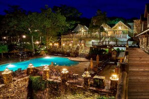 A pool area with a wooden deck, stone walls, and outdoor seating. - Wilderness Club™ at Big Cedar® - 1 Bedroom Lodge (Ridgedale)