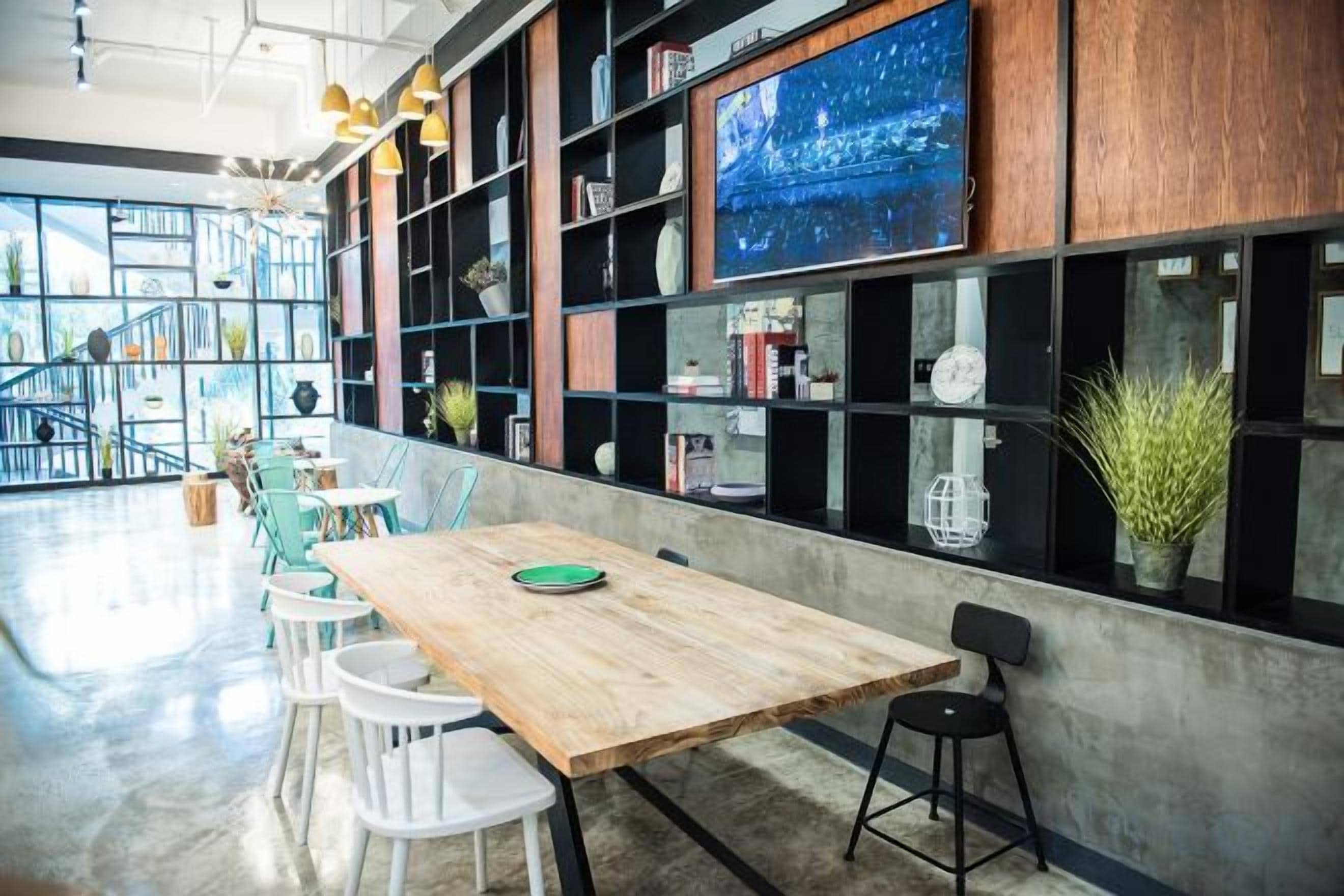 Un interior moderno con una mesa de madera, sillas blancas y estanterías con libros y objetos decorativos.