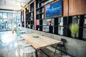 A modern interior with a wooden table, white chairs, and shelves with books and decorative items. - Jinglan LOFT Boutique Hotel (Baishamen Hainan University) (Haikou)