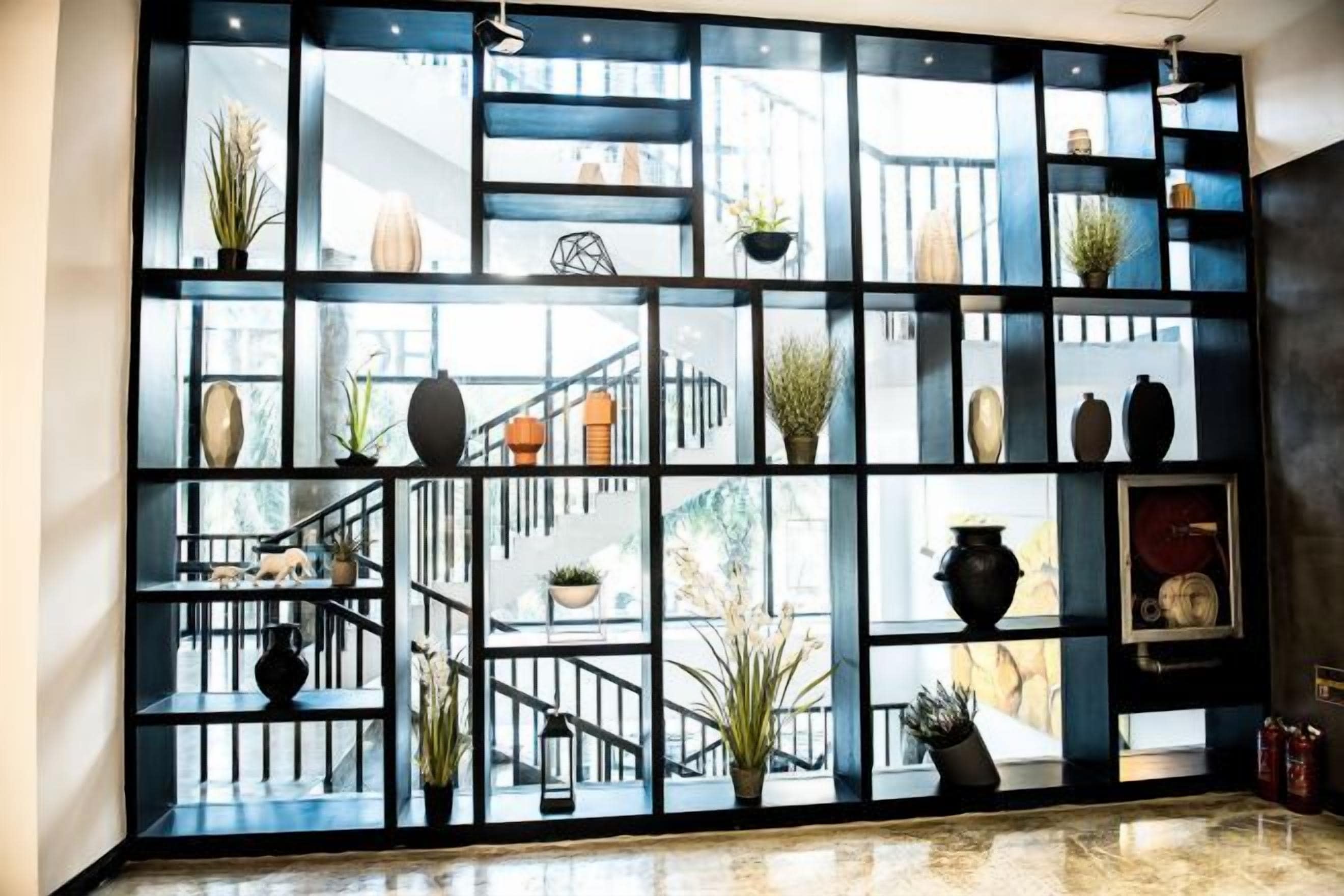 Una estantería metálica negra con varios objetos decorativos y plantas.