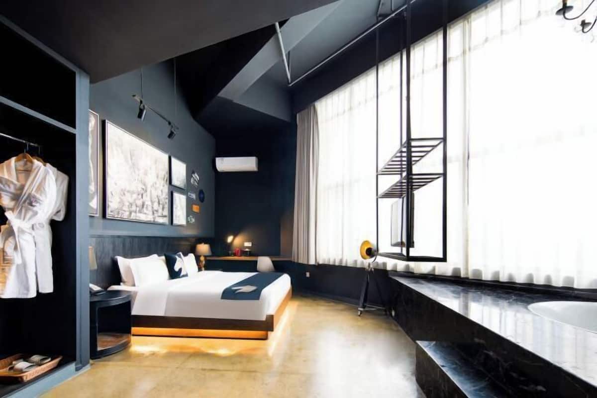 A modern bedroom with a bed, bedside table, and a large window with a view.
