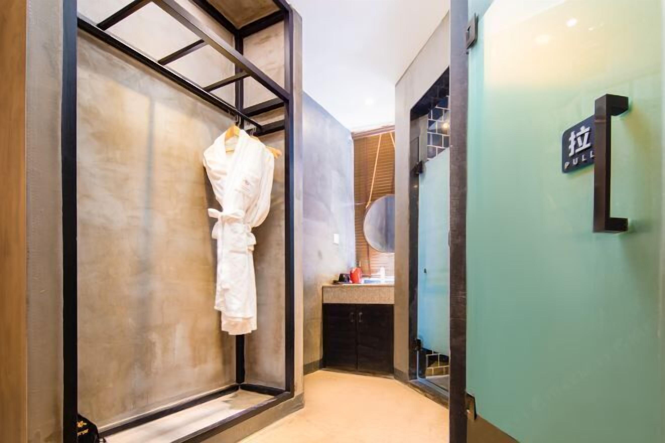 A modern bathroom with a large mirror, a robe hanging on a rack, and a sink with a countertop.