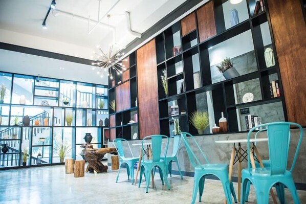 A spacious indoor area with a long table and chairs, a wooden coffee table, and a staircase leading to an upper level. - Jinglan LOFT Boutique Hotel (Baishamen Hainan University) (Haikou)